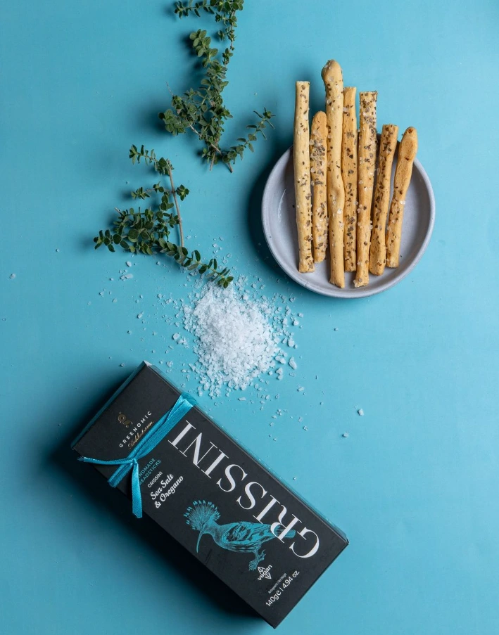 ansprechendes Setbild mit Crissini Packung, sichtbaren Crissinis, Salz und frischen Kräutern